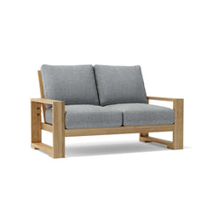 Anderson Teak Capistrano deep seating loveseat with plush cushions in nine designer colors, perfect for outdoor lounging.