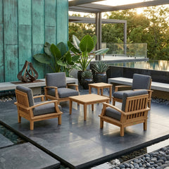 Anderson Teak Brianna teak wood outdoor deep seating set with 4 armchairs and 2 tables, in a garden patio setting with colorful cushions.