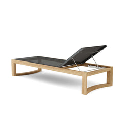 Anderson Teak JUNUS Sun Lounger outdoors with a sleek wooden design and comfortable cushion for relaxing in the sun.